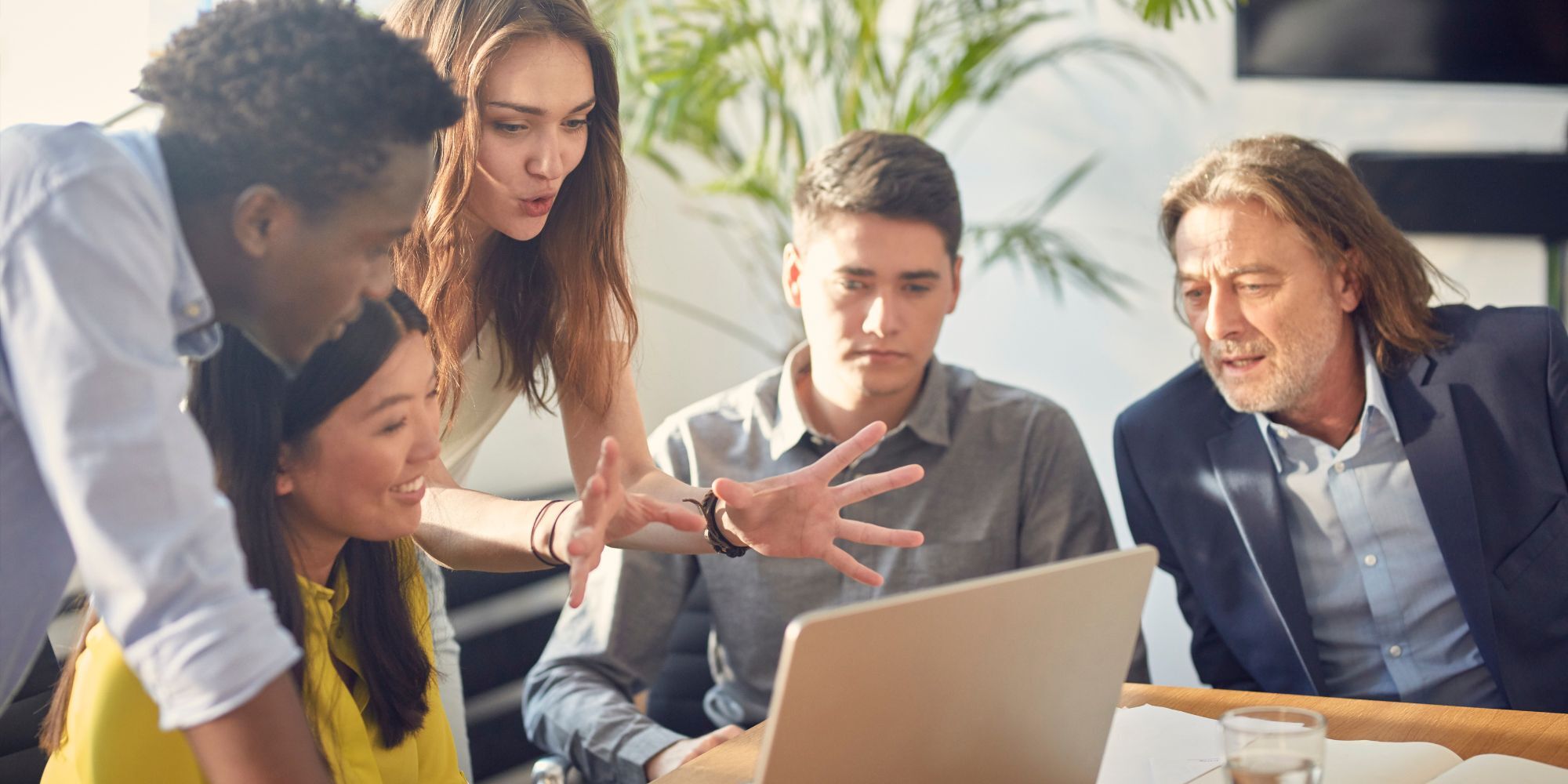 Diverse group of colleagues in discussion in front of a laptop